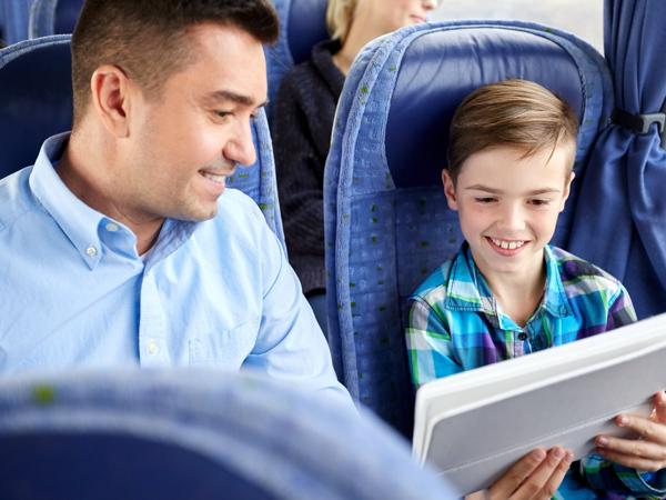 Father and son using tablet on bus