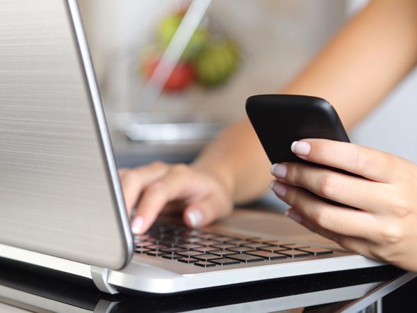 Woman multitasking with phone and laptop