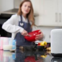 Woman using smart speaker in kitchen