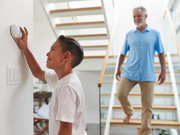 Grandfather and grandson using smart thermostat