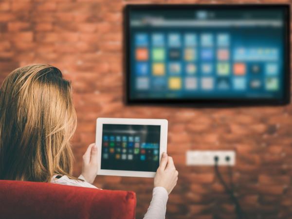 Woman using tablet connected to smart TV