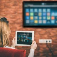 Woman using tablet connected to smart TV