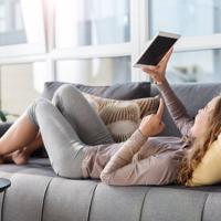 Woman relaxing on couch using streaming device